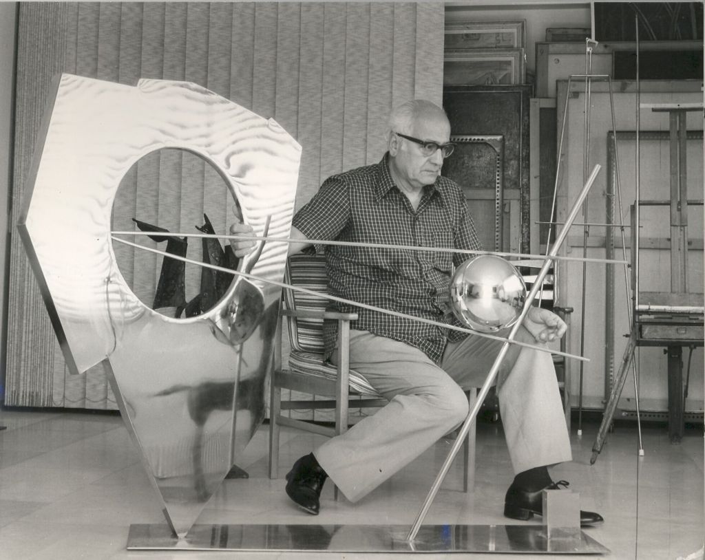 Ο Γιώργος Ζογγολόπουλος στην κατοικία - εργαστήριό του στο Ψυχικό με το γλυπτό του Κενό και σφαίρα , δεκαετία του 1970. © Αρχείο Ιδρύματος Γεωργίου Ζογγολόπουλου
